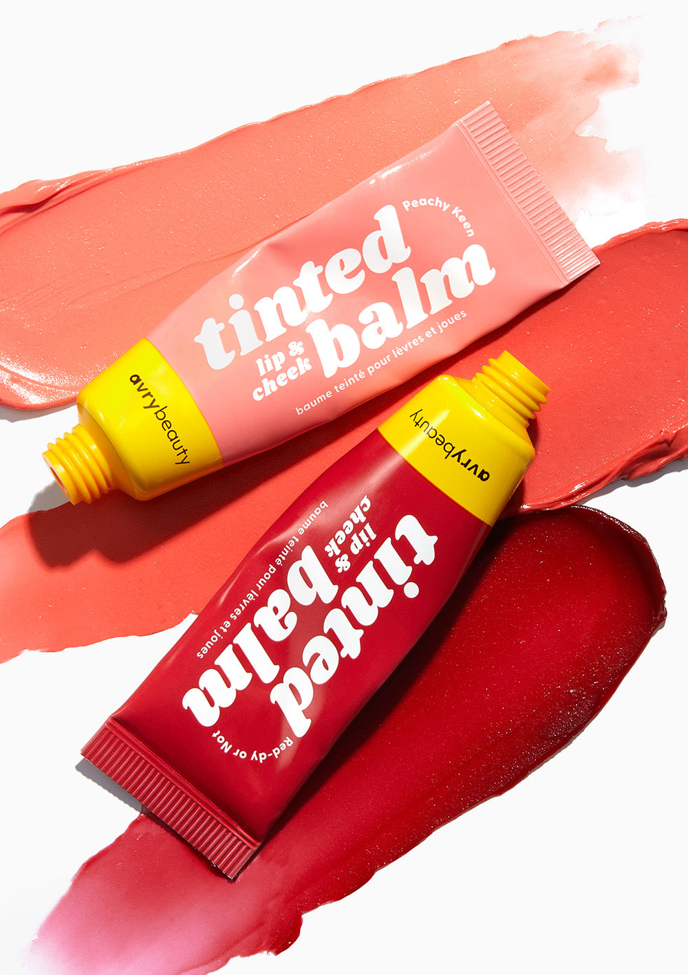 AvryBeauty Red-dy or Not and Peachy Keen Lip & Cheek Tinted Balms displayed on textured swipes, on top of a white background.