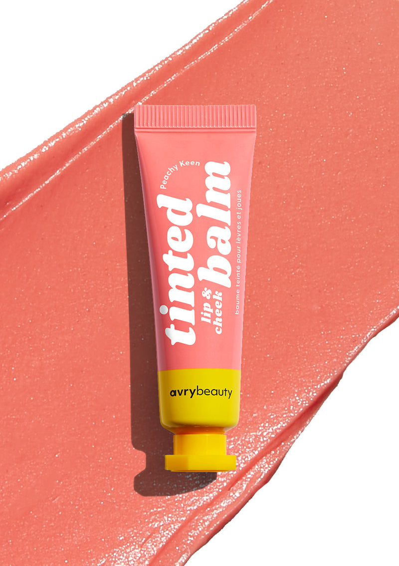 AvryBeauty’s Peachy Keen Lip & Cheek Tinted Balm texture displayed on a white background, with its vegan skincare tube resting atop.