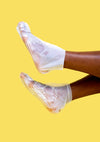 Feet with moisturizing Shea Butter Socks on against a yellow backdrop.