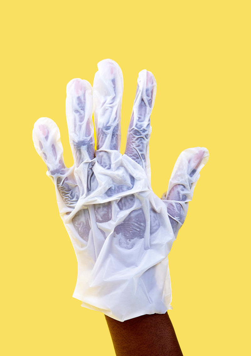 Hand wrapped up in a moisturizing Shea Butter Glove in front of a yellow background.