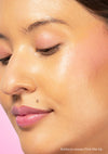 Addison wears Pink Me Up vegan Lip & Cheek Tinted Balm on her cheeks, lips, and eyelids against a soft light pink backdrop.